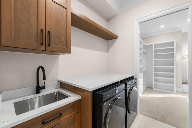 laundry area with washing machine and clothes dryer, sink, cabinets, crown molding, and light carpet