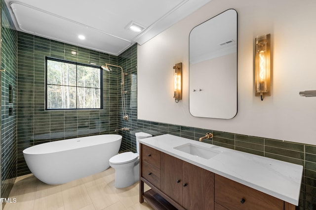 full bathroom with tile patterned floors, vanity, crown molding, tile walls, and toilet