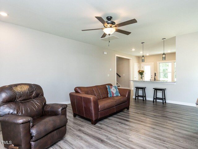 living room featuring ceiling fan, hardwood / wood-style floors, and sink