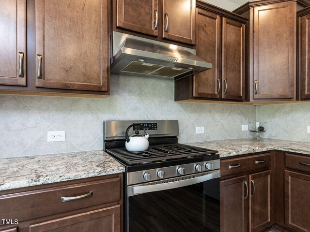 kitchen featuring gas stove, tasteful backsplash, and light stone counters