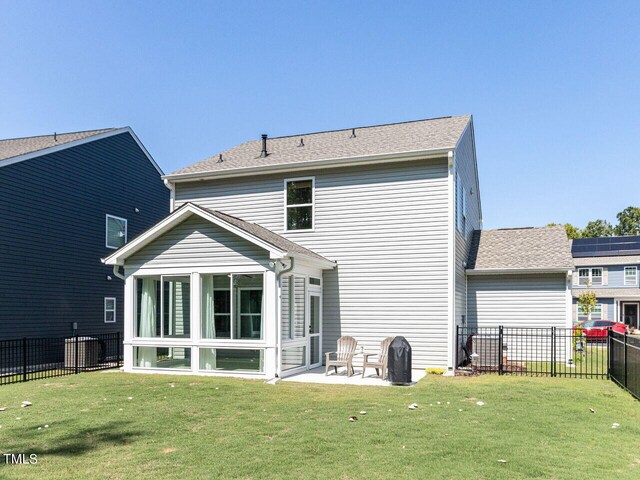 back of house featuring a lawn, a patio area, and a sunroom