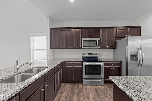 kitchen featuring appliances with stainless steel finishes, light stone countertops, dark hardwood / wood-style flooring, sink, and dark brown cabinetry