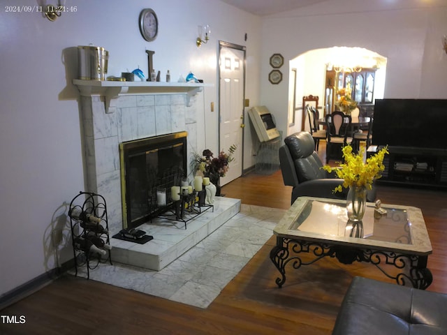 living room featuring wood-type flooring, a tile fireplace, and a notable chandelier