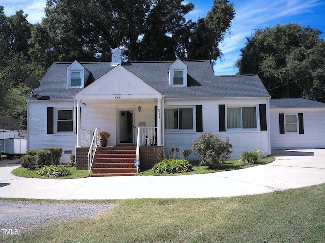 cape cod-style house featuring a front yard and covered porch