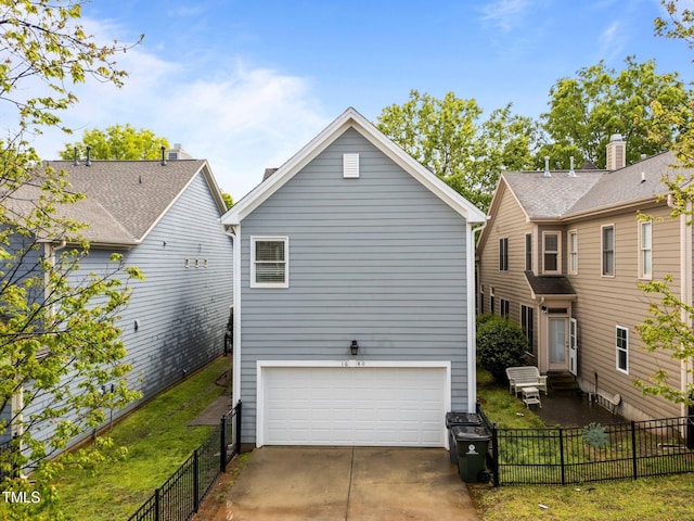 rear view of property featuring an attached garage, entry steps, driveway, and fence