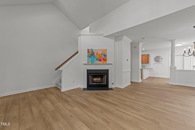 unfurnished living room with light wood-type flooring, stairway, an inviting chandelier, and a fireplace with flush hearth