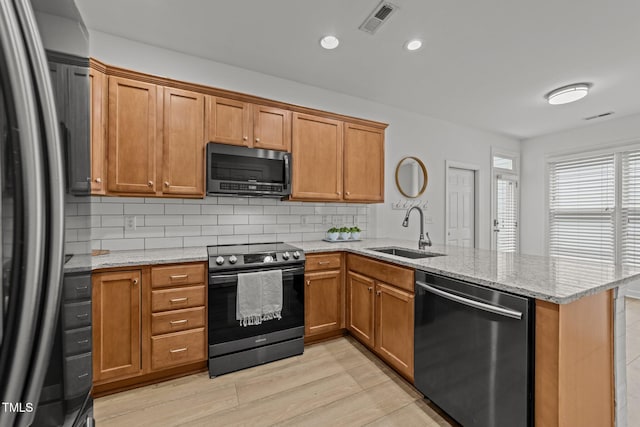 kitchen featuring a peninsula, visible vents, appliances with stainless steel finishes, a sink, and backsplash