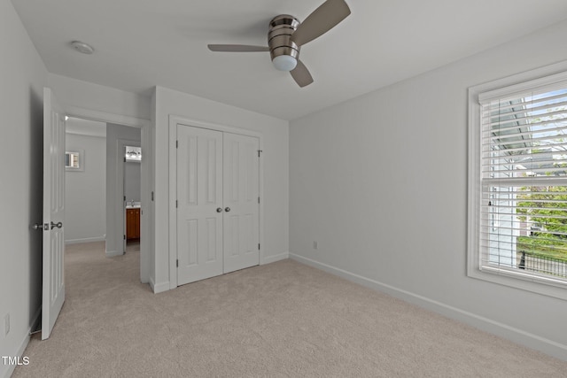 unfurnished bedroom featuring light carpet, a closet, baseboards, and ceiling fan