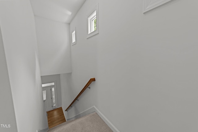 stairs featuring carpet floors, baseboards, and a towering ceiling