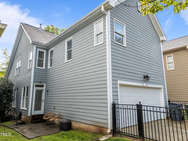 rear view of house featuring a patio, entry steps, fence, and an attached garage