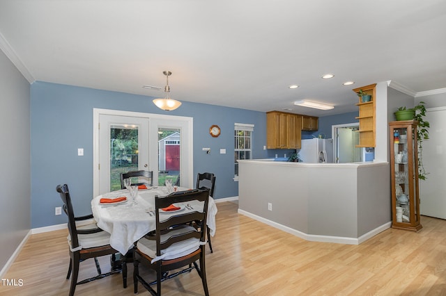 dining area featuring crown molding, light wood-type flooring, and french doors