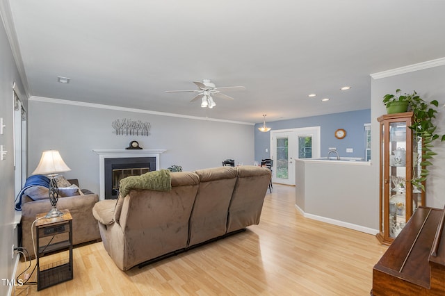 living room featuring light wood-type flooring, ornamental molding, and ceiling fan