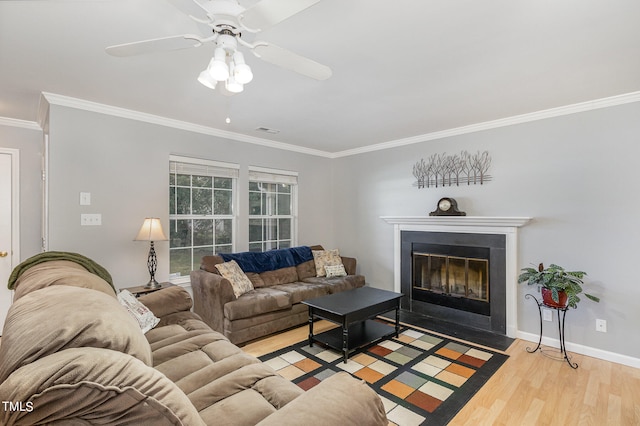 living room featuring ceiling fan, ornamental molding, and light wood-type flooring