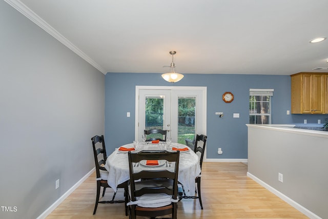 dining area with crown molding, a healthy amount of sunlight, and light wood-type flooring