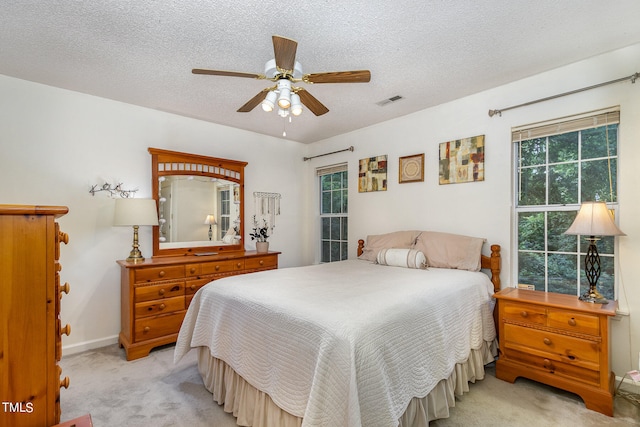 bedroom featuring light carpet, a textured ceiling, and ceiling fan