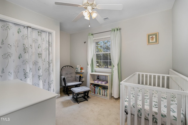 bedroom with ceiling fan, light carpet, and a crib