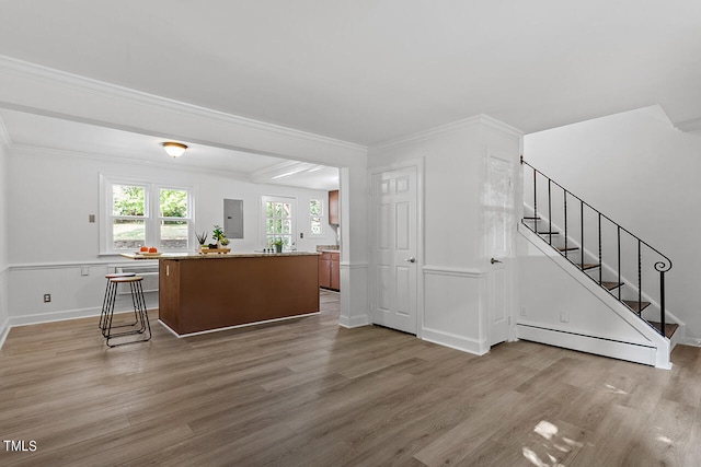 interior space featuring a breakfast bar area, a baseboard radiator, electric panel, a kitchen island, and hardwood / wood-style floors