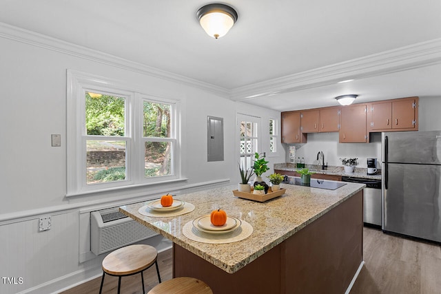 kitchen with sink, crown molding, stainless steel appliances, light hardwood / wood-style floors, and light stone countertops