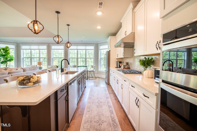 kitchen with white cabinetry, an island with sink, and sink