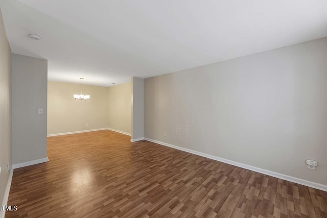 empty room featuring an inviting chandelier and hardwood / wood-style floors