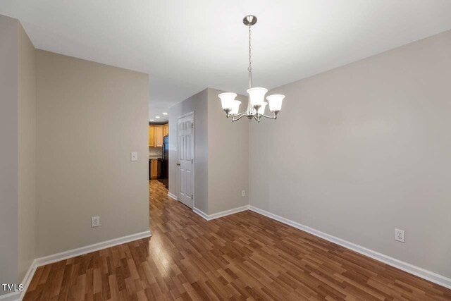 unfurnished dining area featuring a notable chandelier and hardwood / wood-style floors