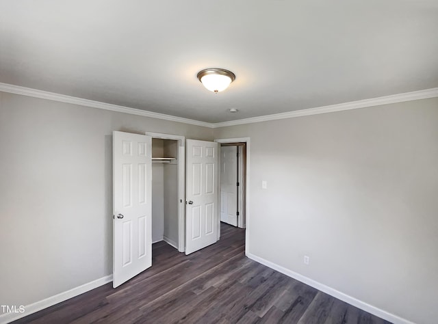 unfurnished bedroom featuring a closet, baseboards, dark wood-type flooring, and ornamental molding