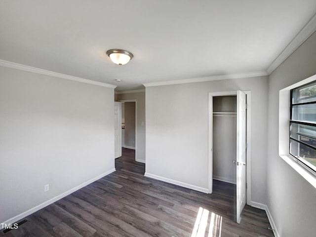 unfurnished bedroom featuring dark wood-style floors, a closet, crown molding, and baseboards