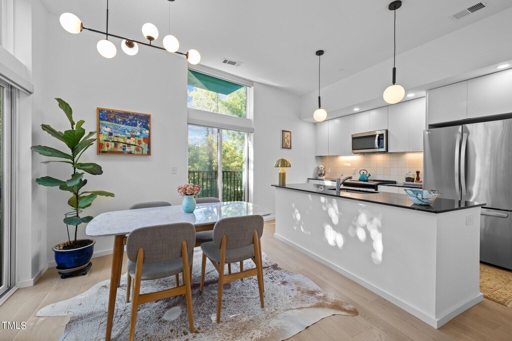 dining area featuring sink, light hardwood / wood-style floors, and a towering ceiling