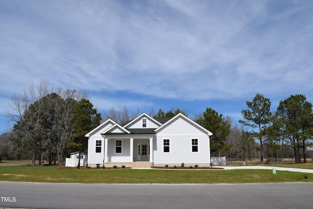 view of front facade featuring a porch, an outbuilding, and a front yard