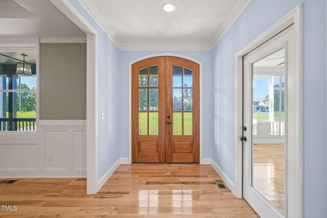 foyer entrance with crown molding, french doors, and light hardwood / wood-style floors