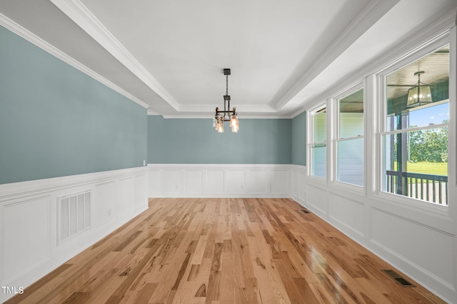 unfurnished room featuring a chandelier, a raised ceiling, light hardwood / wood-style floors, and ornamental molding