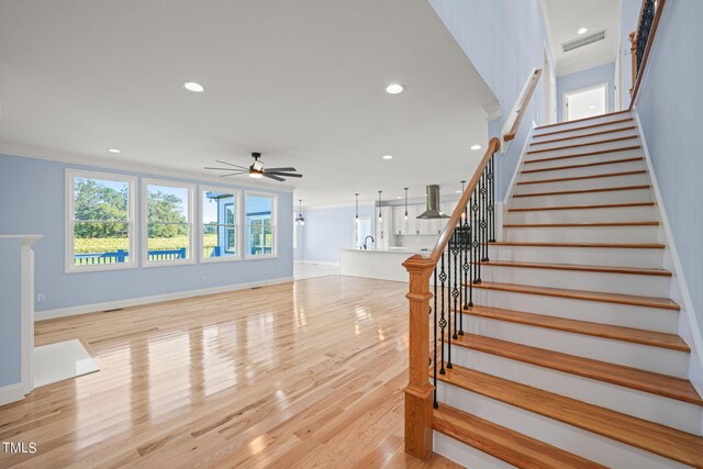 stairs with wood-type flooring and ceiling fan