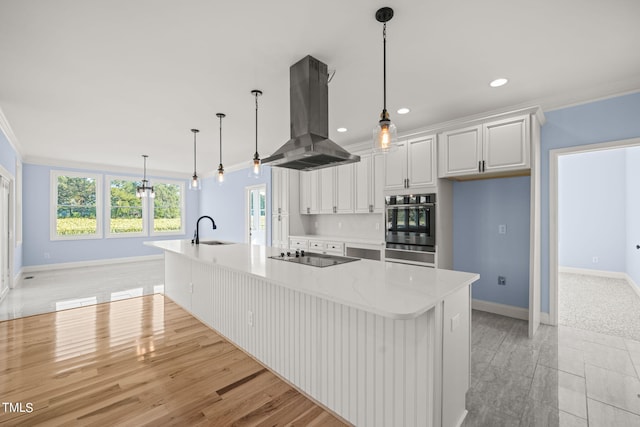 kitchen featuring hanging light fixtures, a large island with sink, white cabinetry, sink, and island range hood