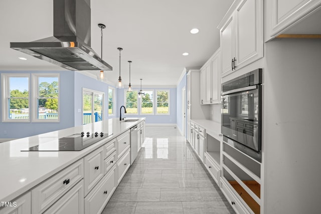 kitchen featuring appliances with stainless steel finishes, hanging light fixtures, sink, white cabinetry, and wall chimney range hood