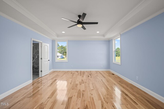 spare room featuring light hardwood / wood-style flooring, ceiling fan, ornamental molding, and a raised ceiling