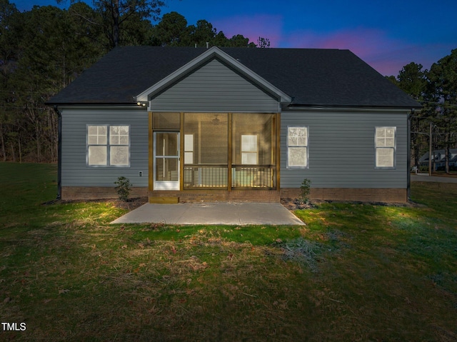 back house at dusk with a yard and a patio area