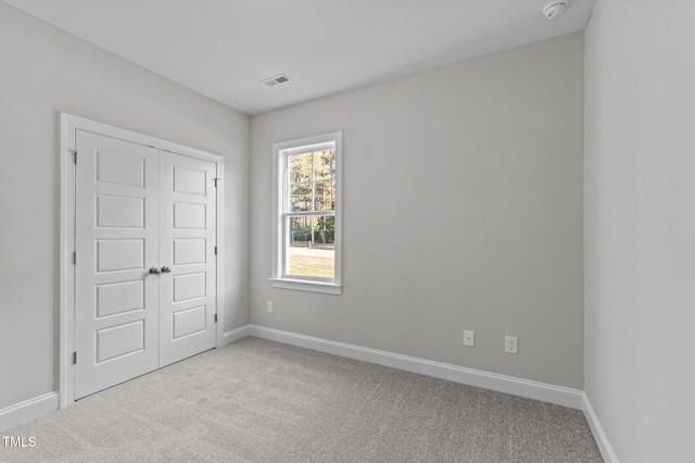 unfurnished bedroom with light colored carpet and a closet