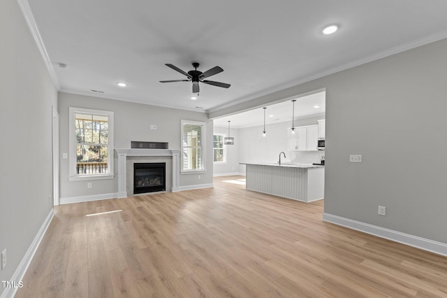 unfurnished living room featuring ceiling fan, light hardwood / wood-style flooring, sink, and ornamental molding