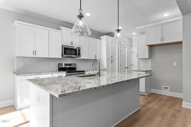 kitchen with white cabinetry, a kitchen island with sink, hanging light fixtures, and stainless steel appliances