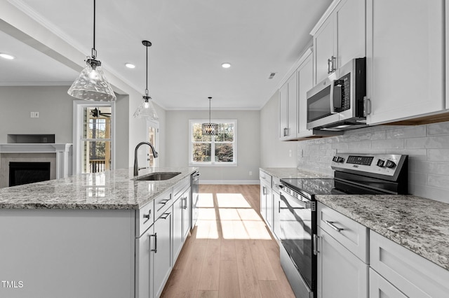 kitchen featuring white cabinetry, sink, stainless steel appliances, an island with sink, and light hardwood / wood-style floors