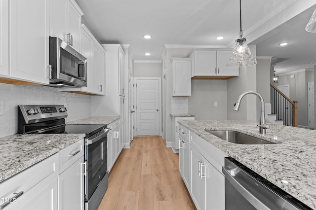 kitchen featuring sink, stainless steel appliances, light hardwood / wood-style flooring, decorative light fixtures, and white cabinets