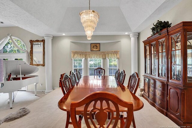 carpeted dining space with a textured ceiling, a chandelier, and ornate columns