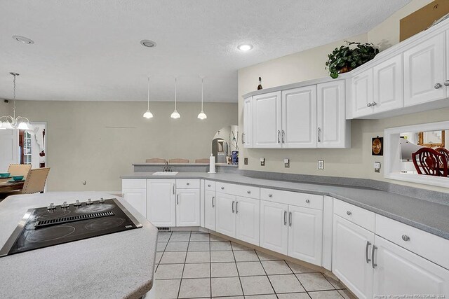 kitchen featuring decorative light fixtures, light tile patterned floors, black electric cooktop, and white cabinetry