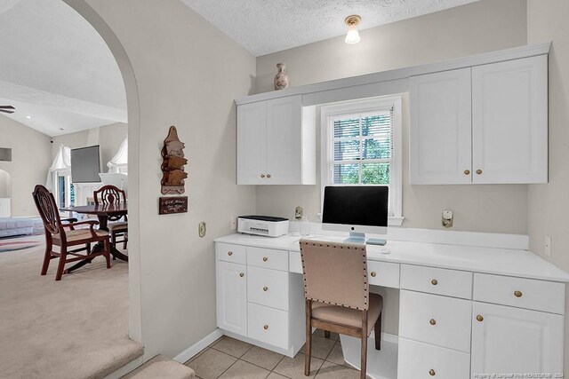 tiled office space featuring built in desk, vaulted ceiling, and a textured ceiling