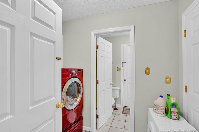 laundry area with washer / dryer, a textured ceiling, and light tile patterned floors