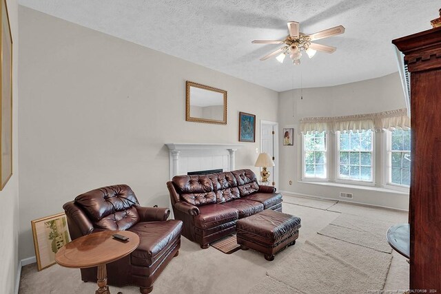 carpeted living room featuring ceiling fan, a fireplace, and a textured ceiling