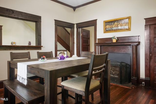 dining space with ornamental molding, a fireplace, and wood finished floors