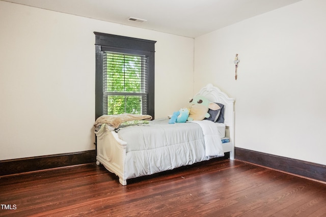 bedroom featuring visible vents, baseboards, and wood finished floors