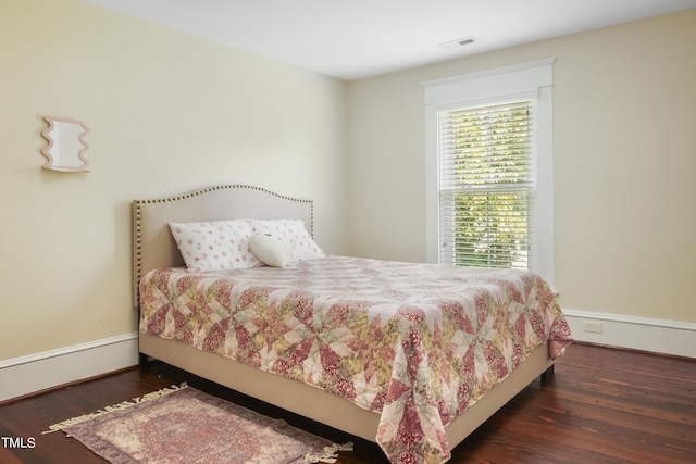 bedroom featuring wood finished floors, visible vents, and baseboards