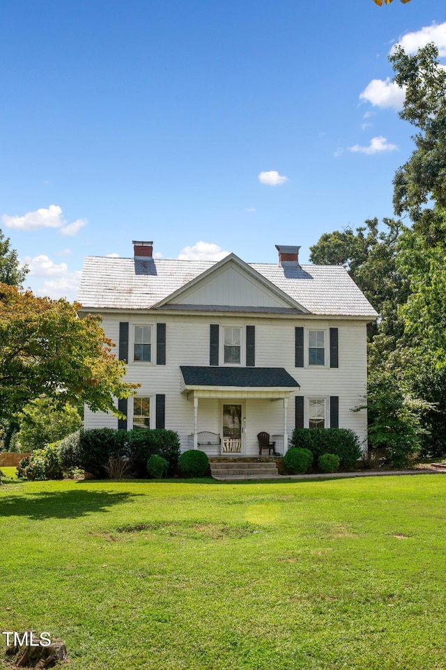 view of front of property with a chimney and a front lawn